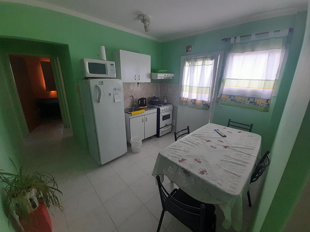 eine Küche mit grünen Wänden, einem Tisch und einem Kühlschrank in der Unterkunft Departamento América in Puerto Madryn