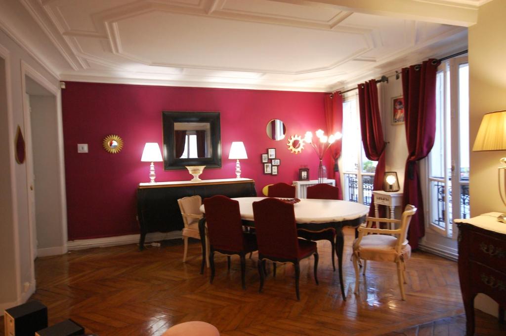 パリにあるTwo-Bedroom Apartment Champs-Elyséesの赤い壁のダイニングルーム(テーブル、椅子付)