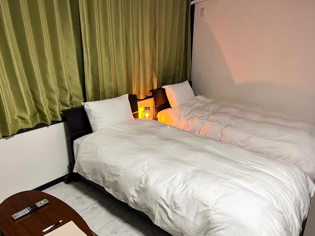 2 Betten in einem kleinen Zimmer mit Fenster in der Unterkunft The Guest House Noah in Naha