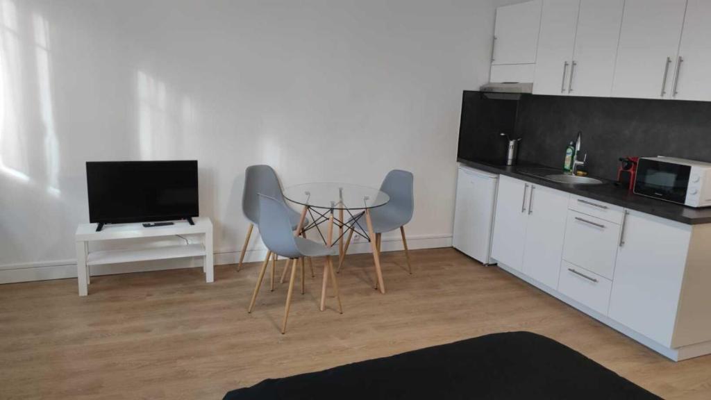 een keuken met een tafel en stoelen en een televisie bij Verdier Studio Lot 5 in Toulouse