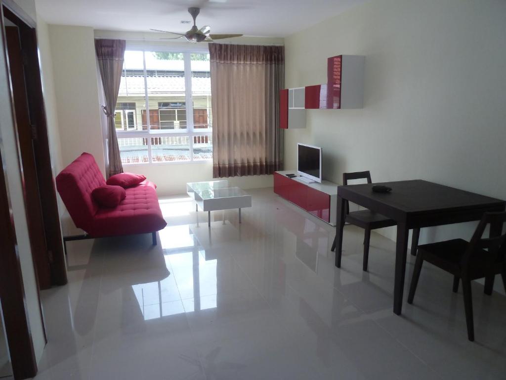 ein Wohnzimmer mit einem roten Stuhl und einem Tisch in der Unterkunft Gib Apartment in Surin