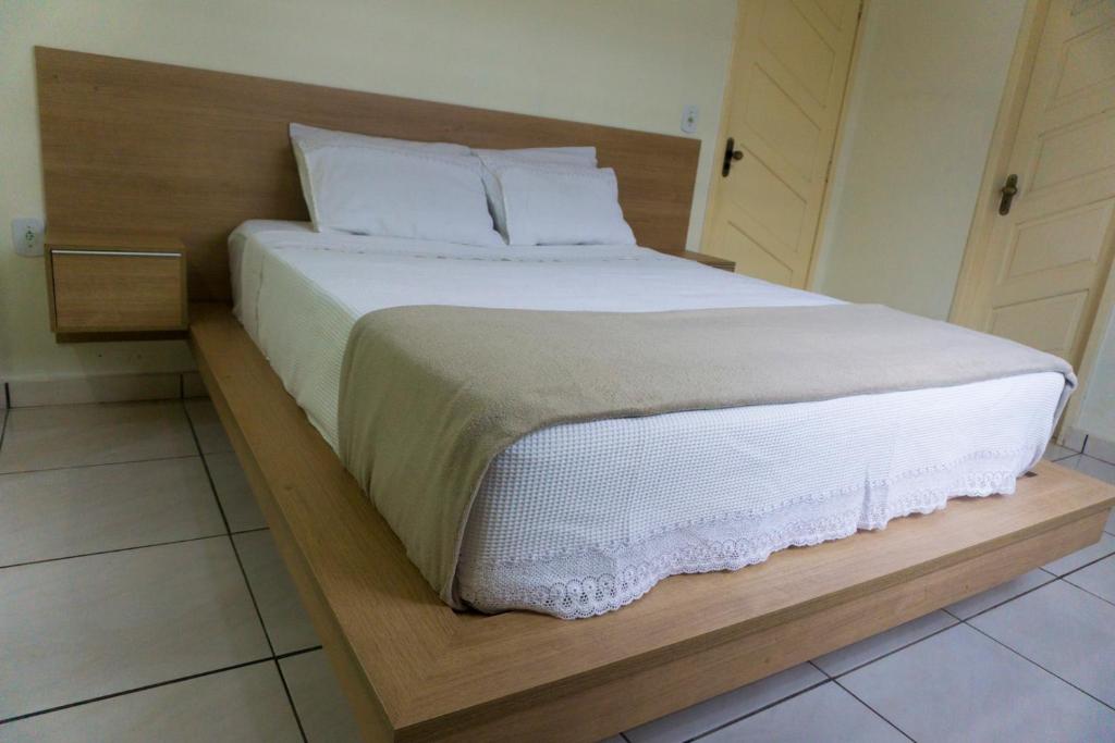 uma cama com lençóis brancos e almofadas num quarto em Casa Linda em Santarém
