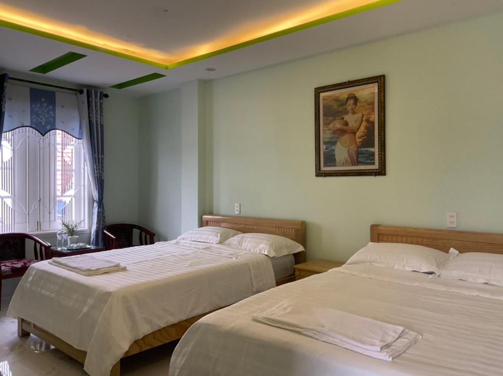 1 dormitorio con 2 camas y una foto en la pared en An Na Bình Homestay en Hoi An