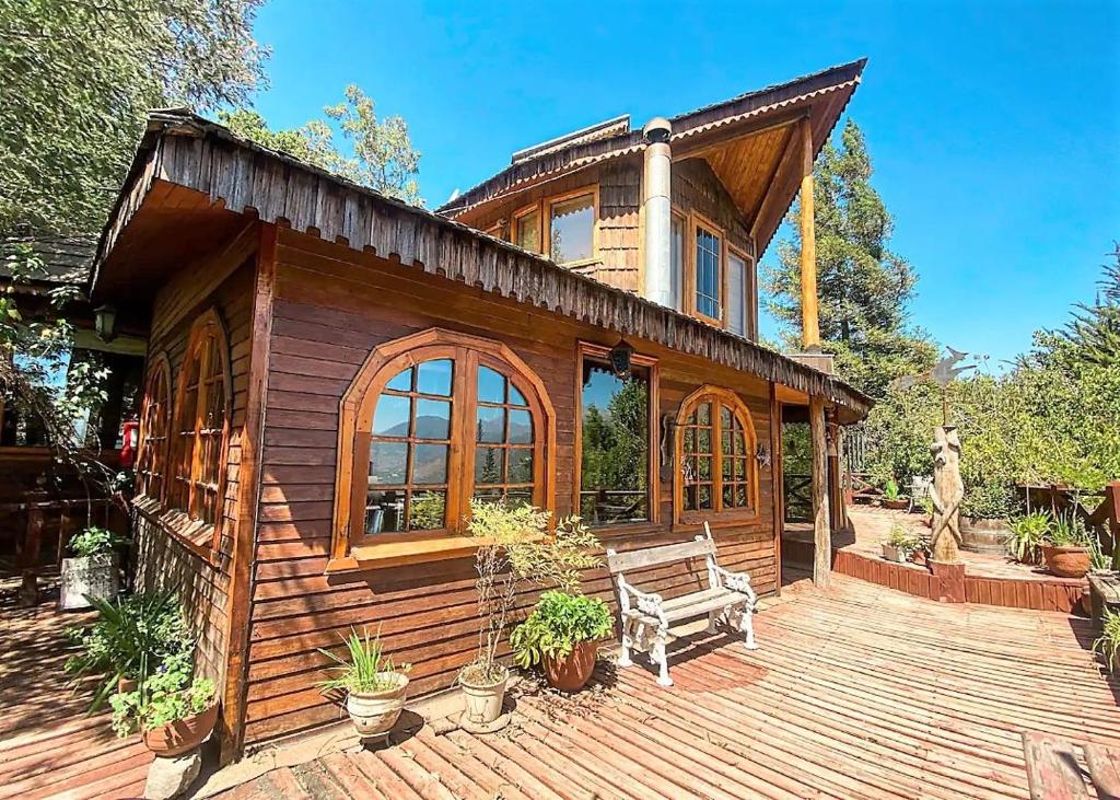 a wooden house with a bench on a deck at Refugios de la Montaña in San José de Maipo