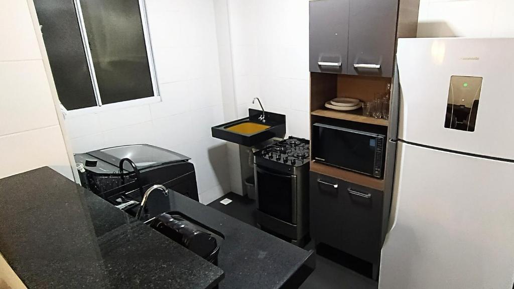 uma pequena cozinha com um frigorífico e um fogão em Apto Executivo Ravena em Campo Grande