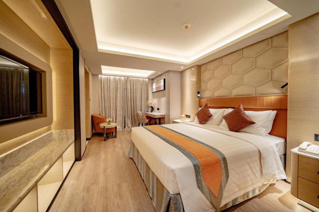 ein Hotelzimmer mit einem großen Bett und einem TV in der Unterkunft Hotel Golden Dragon in Macau