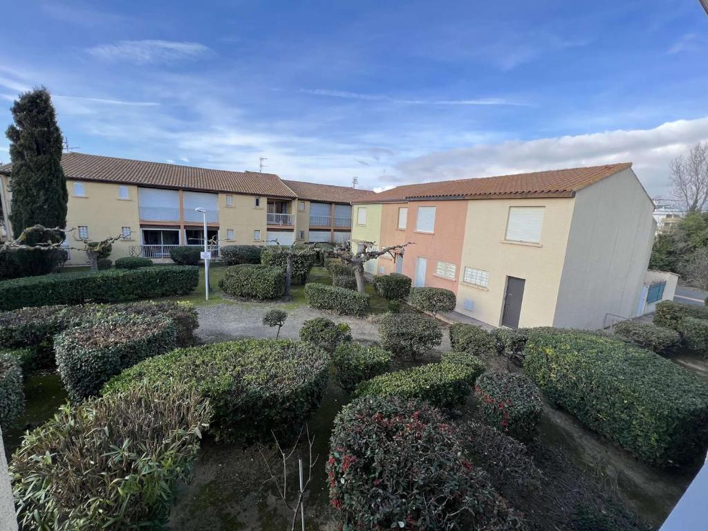 un jardin en face d'un immeuble avec des buissons dans l'établissement Studio près de la plage, cabine, parking privatif, 4 pers, 1er étage, Valras-Plage - FR-1-701-2, à Valras-Plage