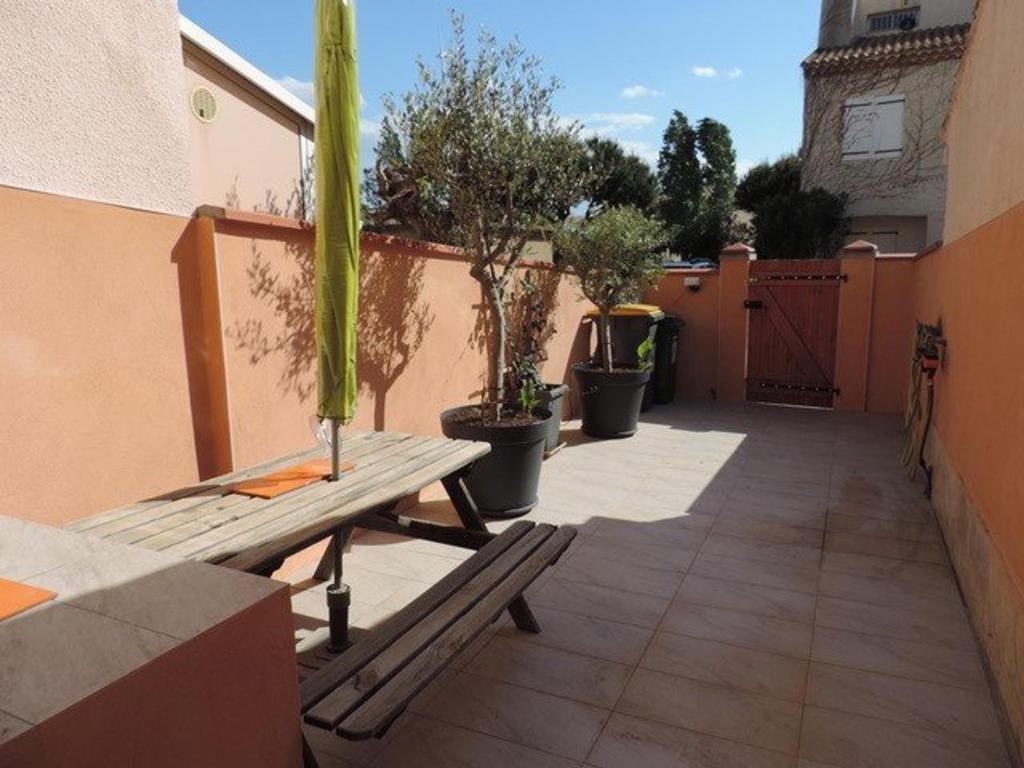 une terrasse avec un banc en bois et des plantes en pot dans l'établissement Maison 7 Pers. à Valras-Plage avec BBQ, Terrasse et Proche Port - FR-1-701-1, à Valras-Plage