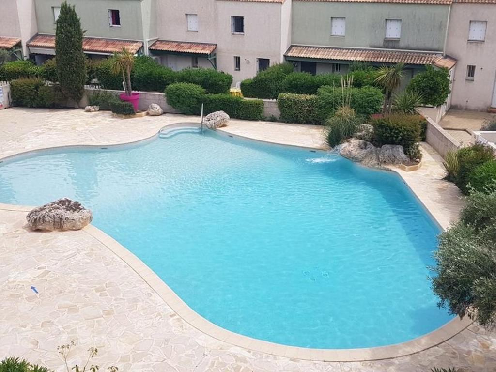 une grande piscine bleue devant un immeuble dans l'établissement Charmant Pavillon avec Terrasse, Piscine et Parking, Proche Plage et Commerces - 6 pers. - FR-1-701-32, à Valras-Plage