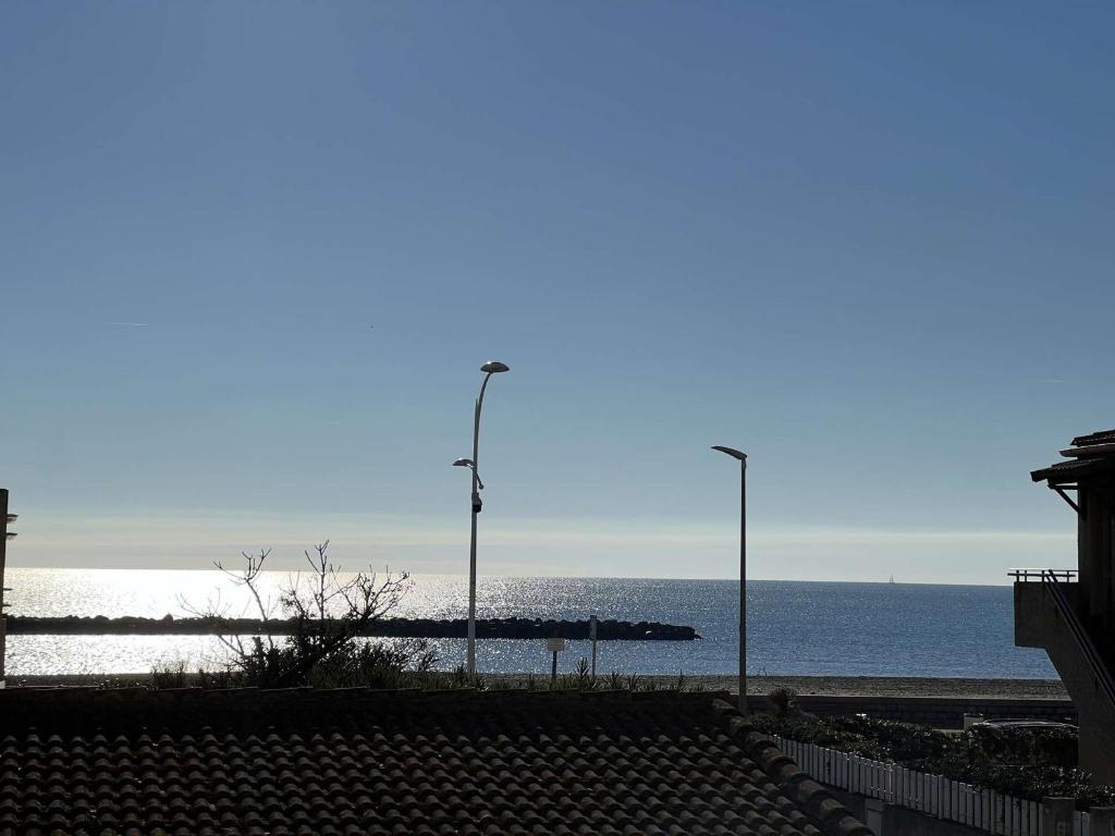een strand met twee straatverlichting en de oceaan bij Appartement Valras-Plage, 1 pièce, 4 personnes - FR-1-701-21 in Valras-Plage