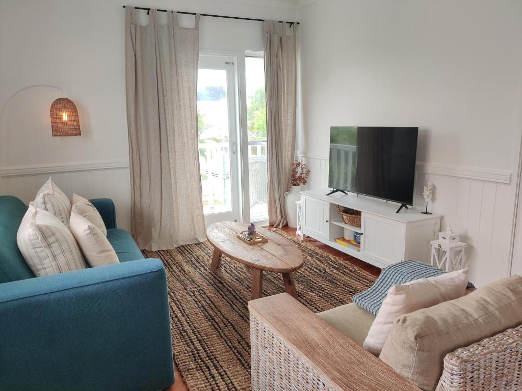 un soggiorno con divano blu e TV di Eugarie Seaside Guesthouse a Marcoola