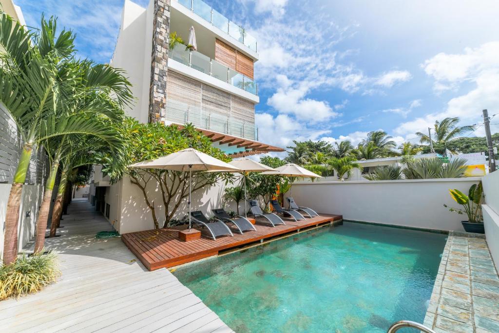 a pool with chairs and umbrellas next to a building at Beachcove Apartment 9 in Pereybere in Pereybere