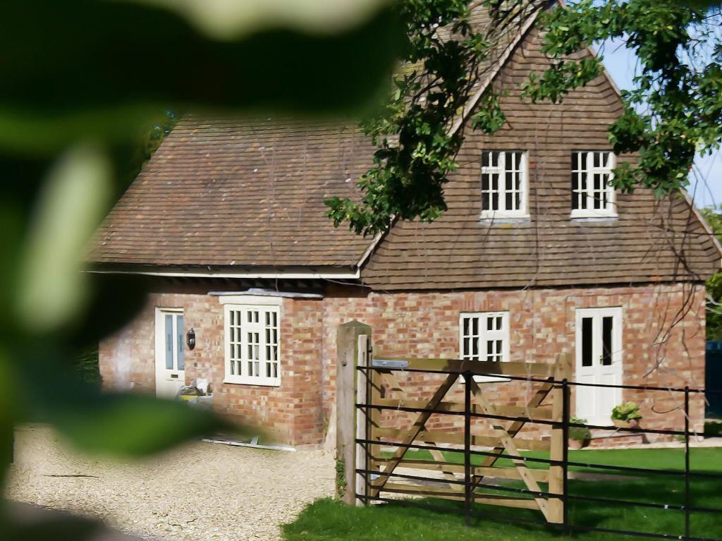 ein altes Backsteingebäude mit weißen Fenstern und einem Tor in der Unterkunft Oak Tree Cottage in Stoke Rochford