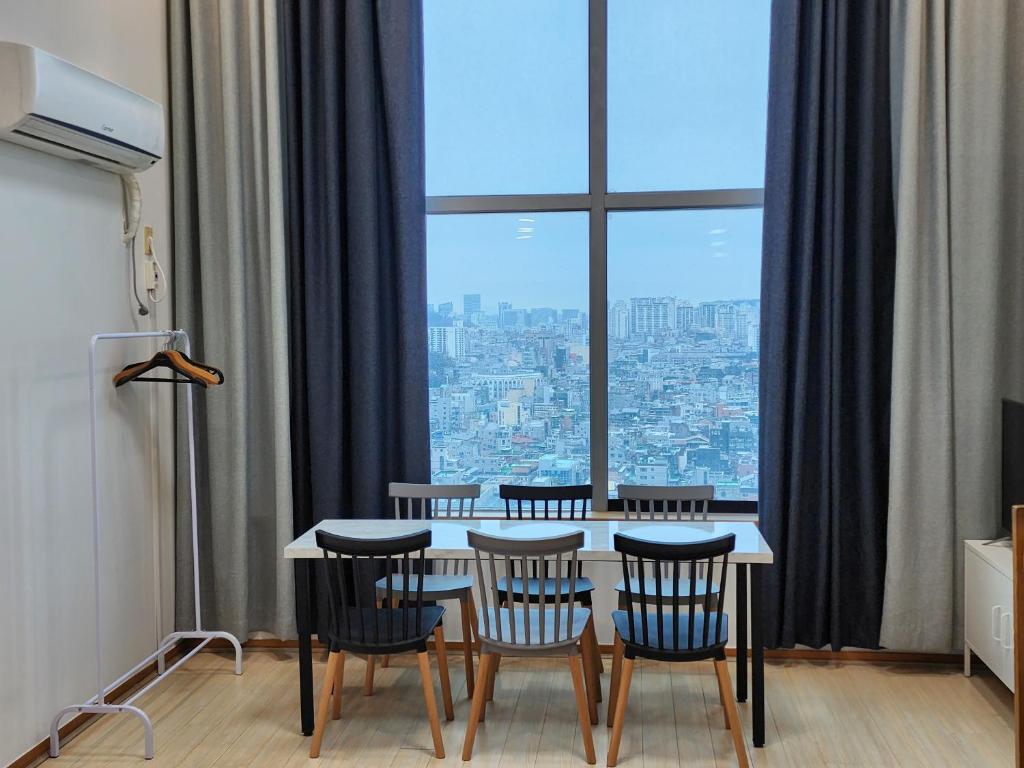 a dining room table with chairs and a large window at JSM Studio Hongdae in Seoul