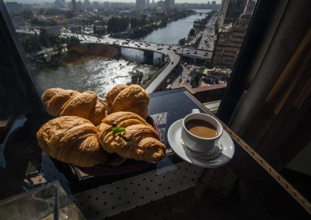 開羅的住宿－River Nile Edge Boutique Hotel & Restaurant，一张桌子,上面放着一盘糕点和一杯咖啡