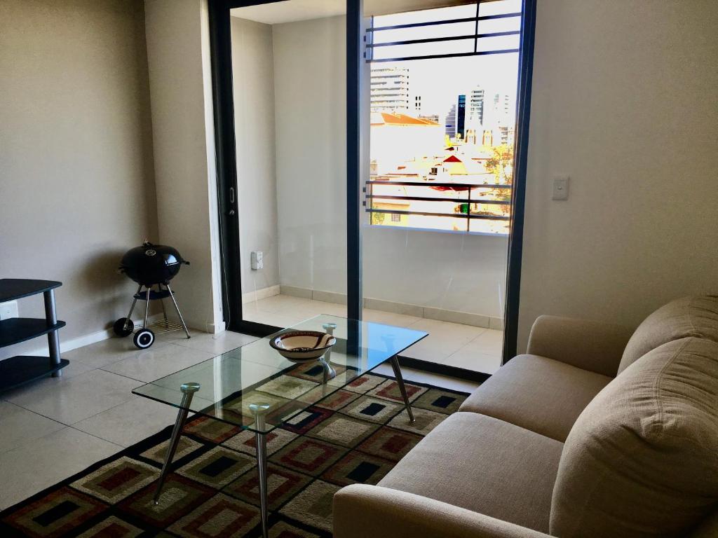 un soggiorno con divano e tavolo in vetro di City Junction a Windhoek