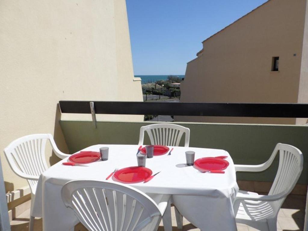 - une table blanche avec des chaises blanches et des assiettes rouges dans l'établissement Appartement 2 pièces 6 couchages, terrasse, parking privé, sud - FR-1-326-458, à Marseillan