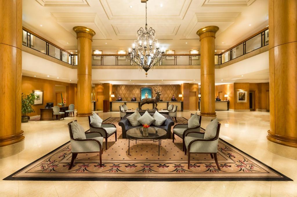 a lobby with a couch and chairs and a chandelier at Millennium Gloucester Hotel London in London