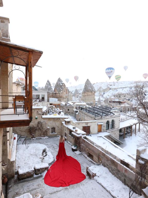 uma mulher de vestido vermelho em cima de um edifício em Naraca Cave House em Goreme