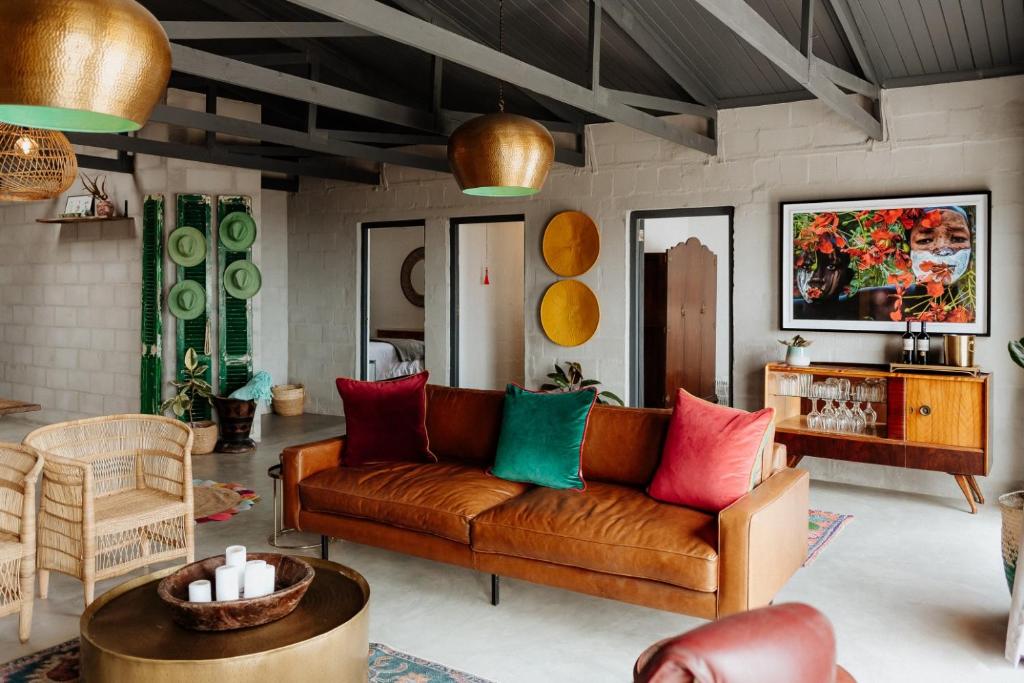 a living room with a brown couch with colorful pillows at Sea Siren in Paternoster