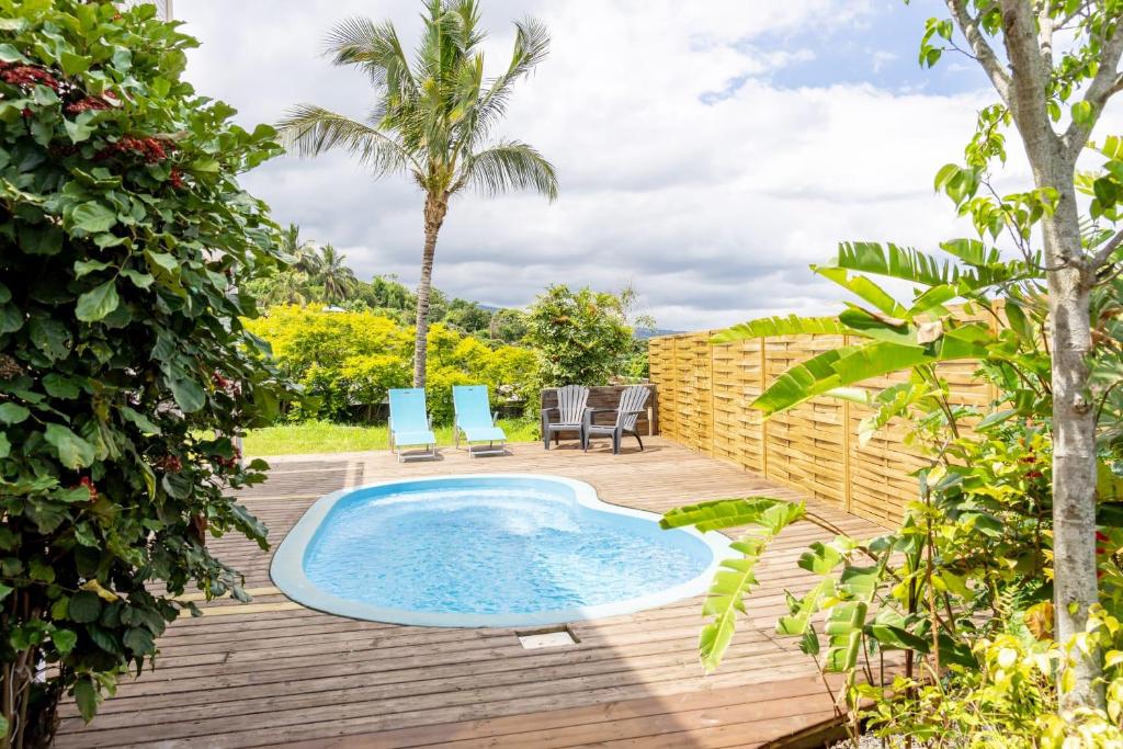 una piscina su una terrazza con due sedie e una palma di Au Bois Bichette a La Possession