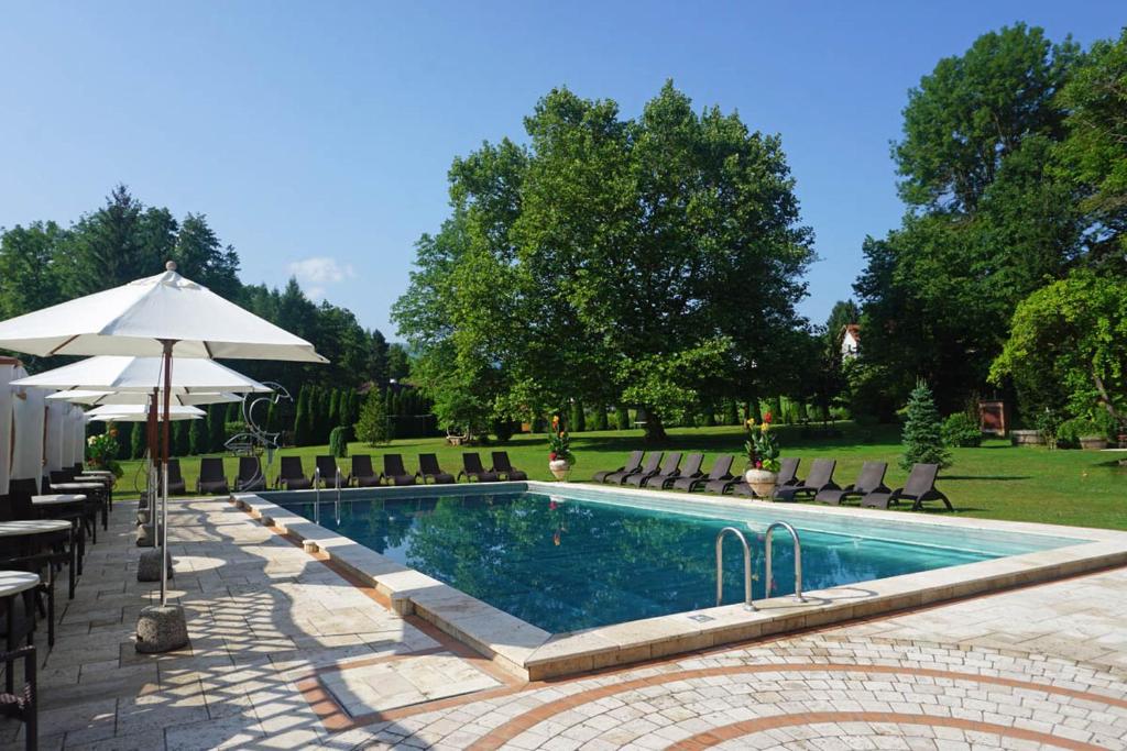 a swimming pool with chairs and an umbrella at Gartenhotel Kloepferkeller in Eibiswald