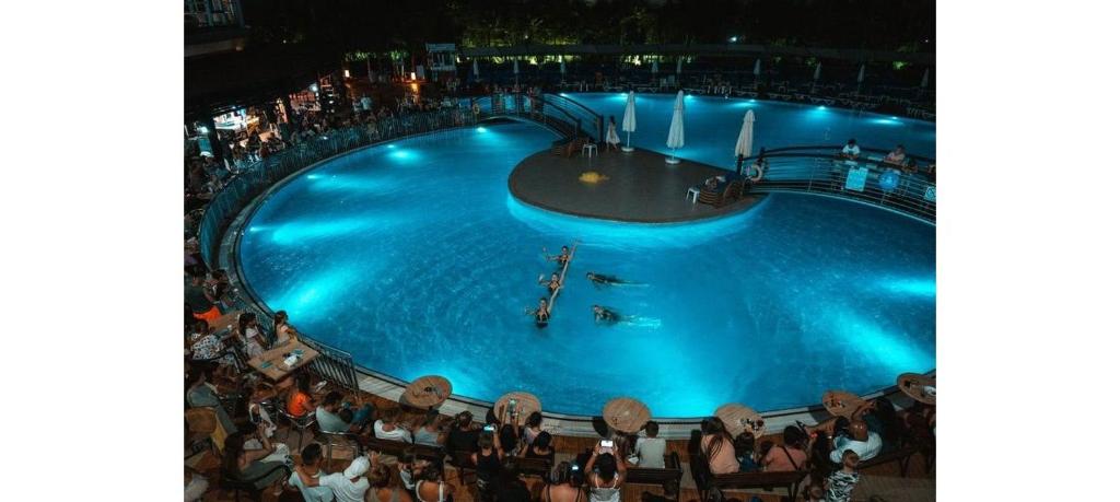 een menigte mensen die 's nachts rond een zwembad staan bij Side Luxury All Inclusive Random Rooms by LookBookHoliday in Side
