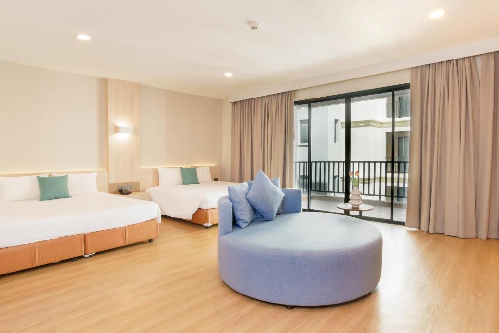 a hotel room with two beds and a chair at Mike Garden Resort - SHA EXTAR PLUS in Pattaya