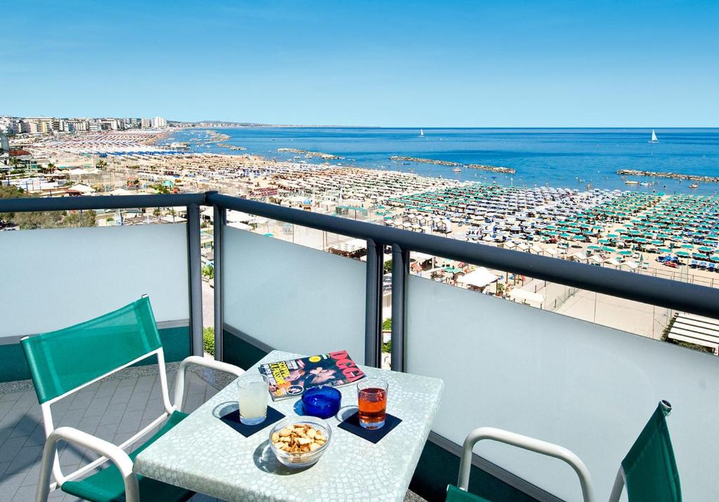 un tavolo e sedie su un balcone con vista sulla spiaggia di Hotel Flaminio a Cattolica