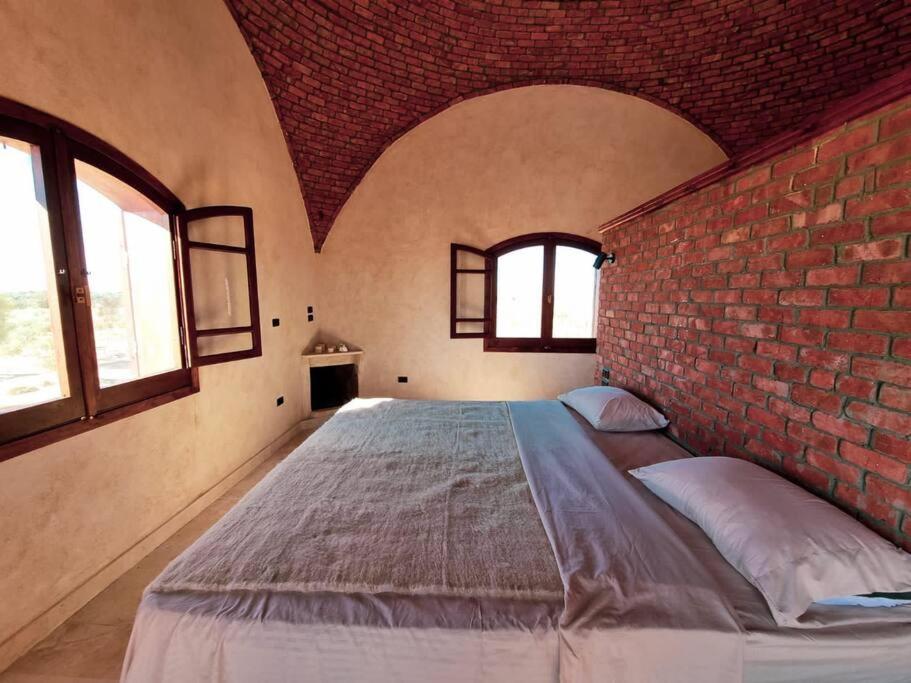 a bedroom with a large bed with a brick wall at A Home with a Dome in ‘Izbat Ţanāţī