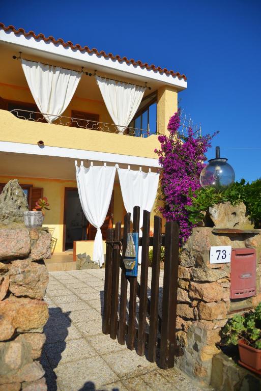 a fence in front of a house with white curtains at Casa UGB in Cannigione
