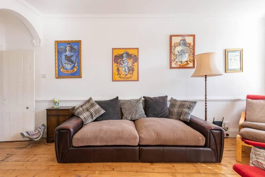 a brown leather couch in a living room with pictures on the wall at Medieval roots and Harry Potter TownHouse - Hiking near Ludlow in Leominster