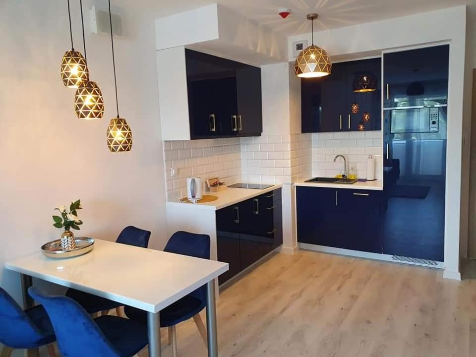 een keuken met een witte tafel en blauwe stoelen bij Apartament Kołobrzeg in Kołobrzeg
