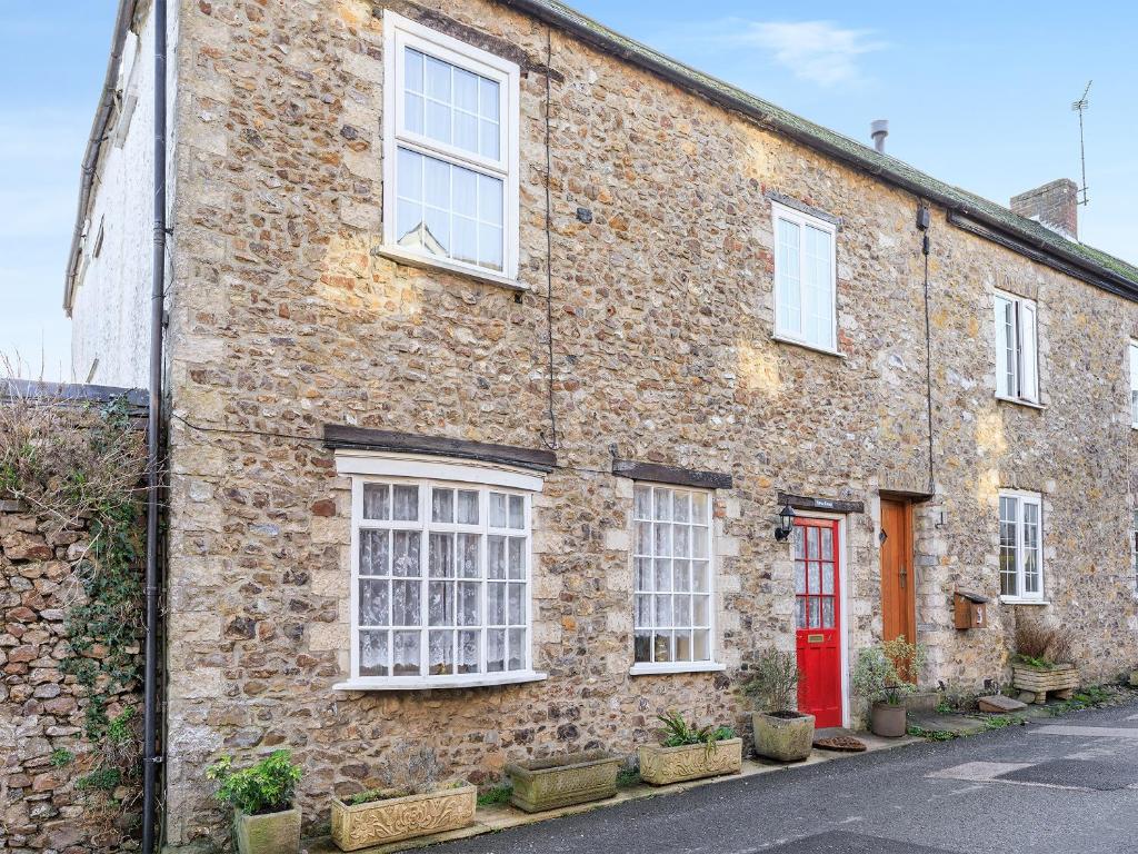 an old brick house with a red door at Harvey Cottage in Colyton