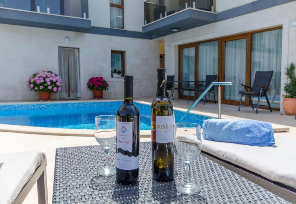 dos botellas de vino en una mesa junto a una piscina en Villa LA en Veliki Drvenik