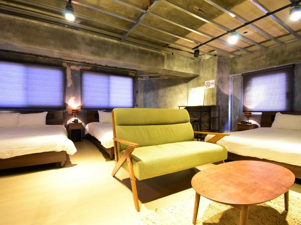a bedroom with two beds and a chair and a table at Urban Life Matsuda - Vacation STAY 85183 in Okayama