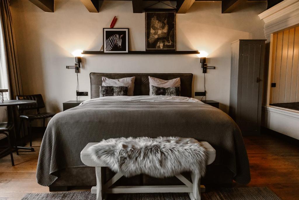 a bedroom with a large bed with a black comforter at Hotel Chapter in 's-Gravenzande