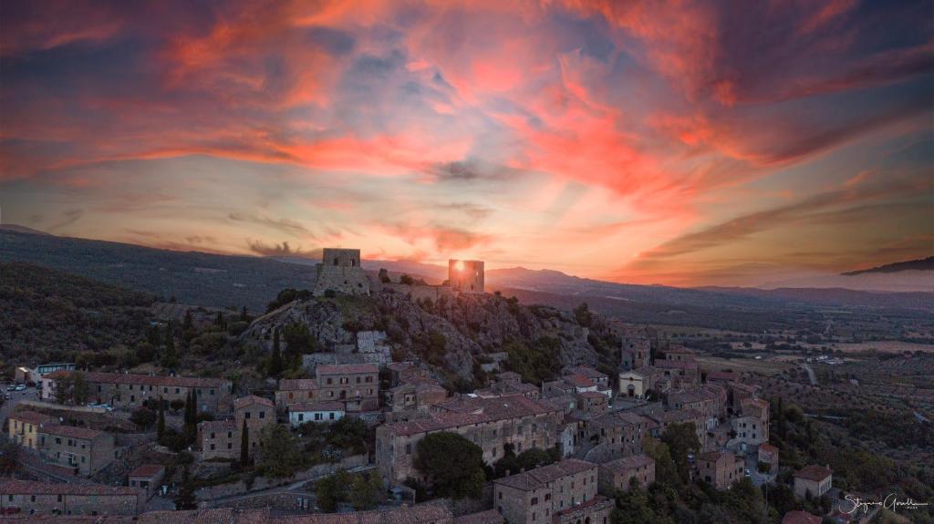 a city with a castle on a hill at sunset at diVO Little Boutique Home in Montemassi