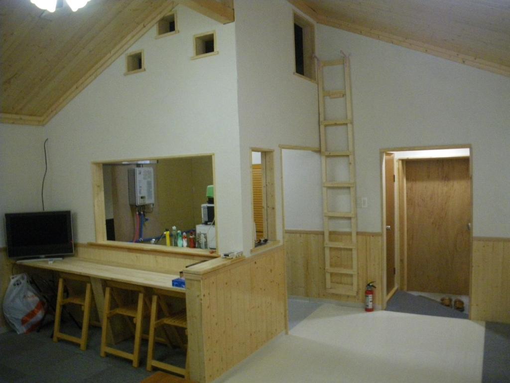 a room with a kitchen with a counter and a ladder at すまいるハウス in Teine