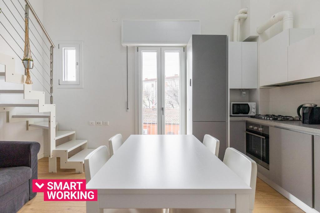 uma cozinha branca com uma mesa e cadeiras brancas em Appartamento a Porta Lame by Wonderful Italy em Bolonha