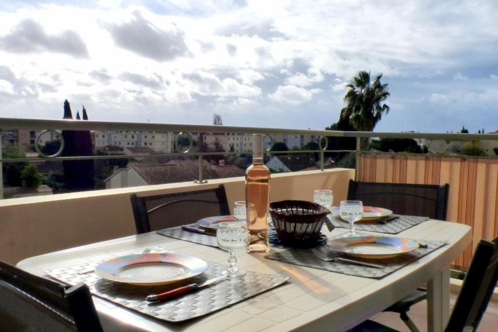 - une table avec des assiettes et des verres à vin sur un balcon dans l'établissement 34m south facing with terrace and open view, à Sanary-sur-Mer