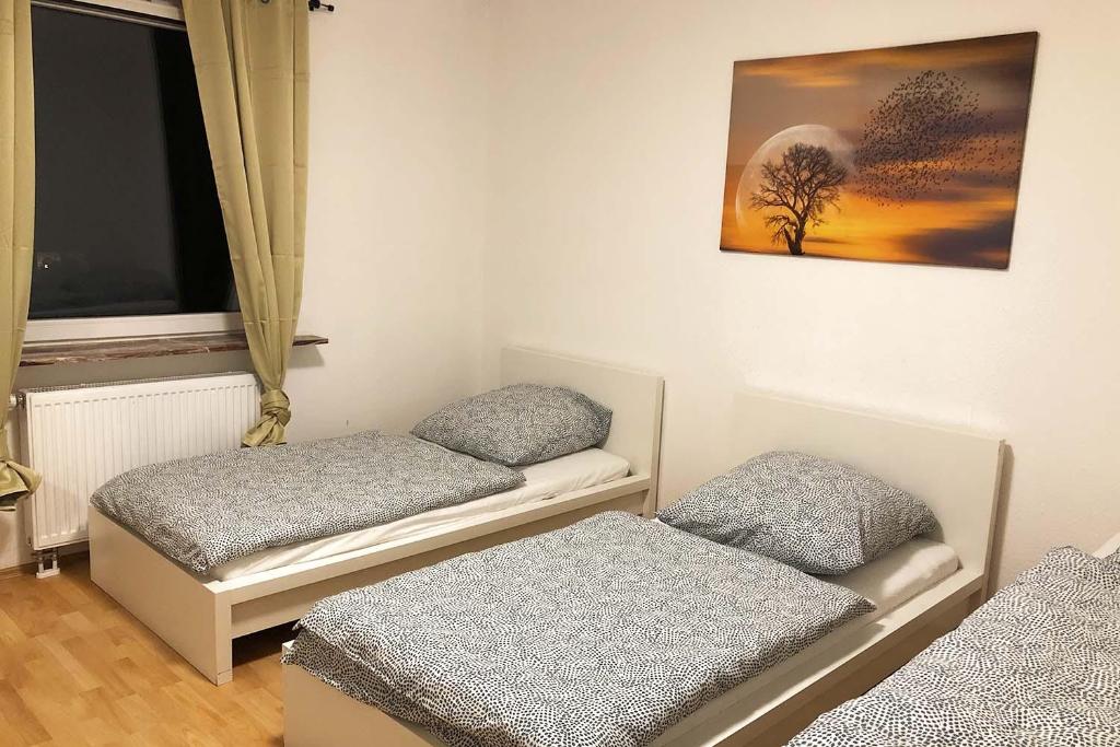 2 Einzelbetten in einem Zimmer mit Fenster in der Unterkunft cozy Apartments with WiFi in Oberhausen