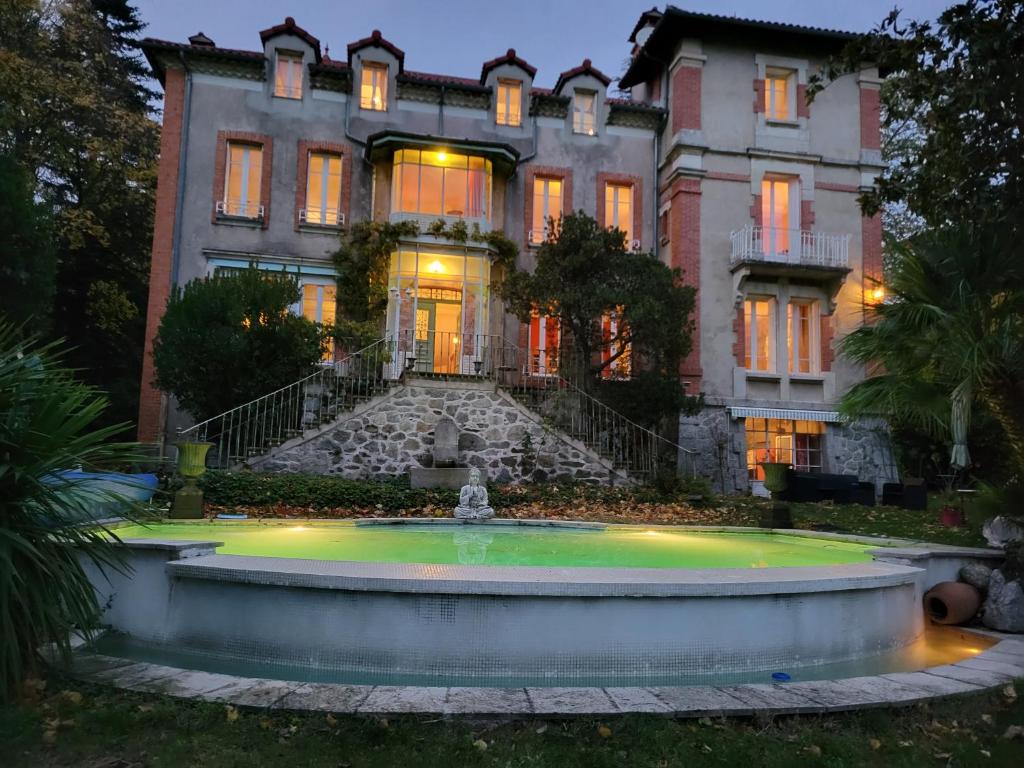 a mansion with a fountain in front of it at Le Temps des Cerises in Génolhac