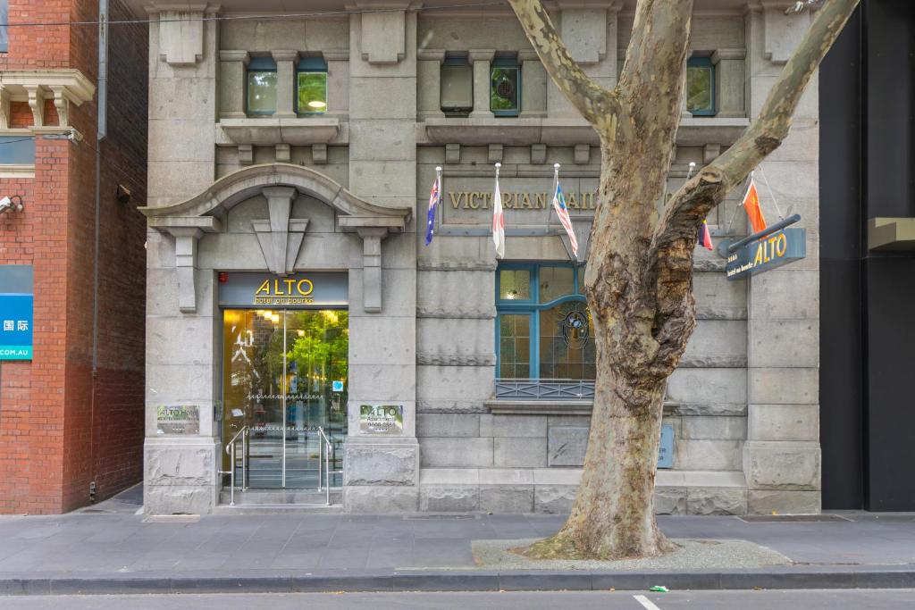 un edificio con un árbol delante de él en Alto Hotel On Bourke en Melbourne