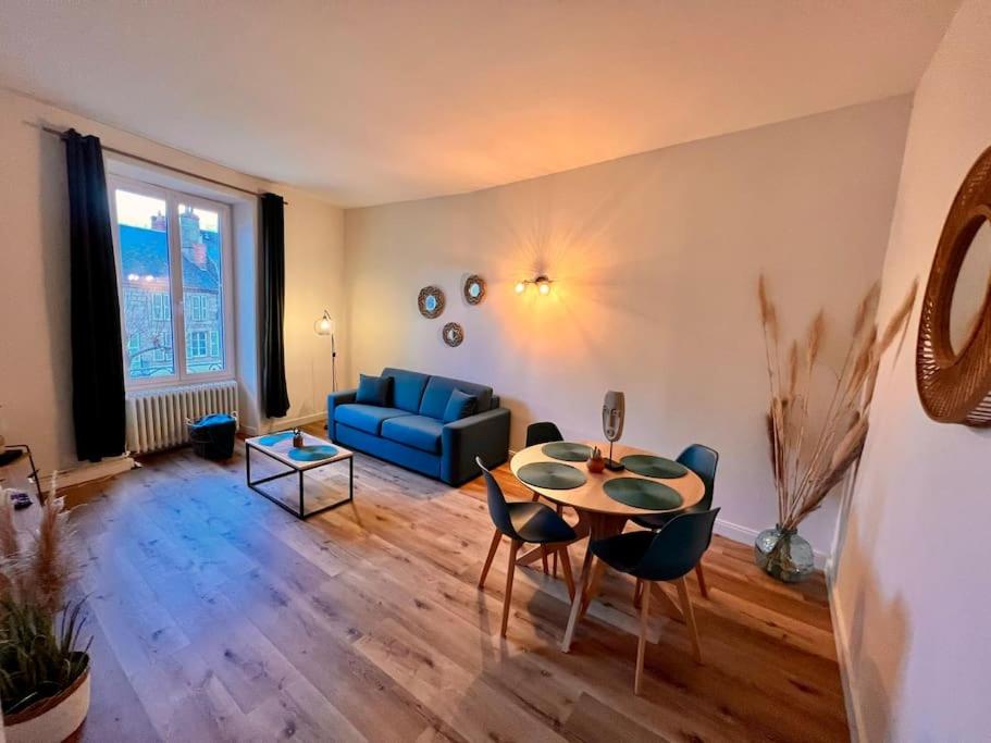 - un salon avec une table et un canapé bleu dans l'établissement Casa Teyssier #3 - Joli & Paisible T3 - Hyper Centre Brive, à Brive-la-Gaillarde