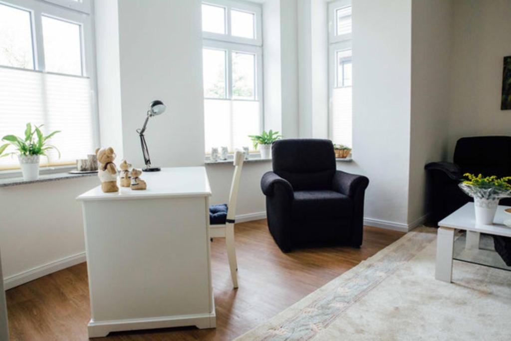 a living room with a black chair and a table at Villa Schönfeld Wohnung 1 in Papenburg