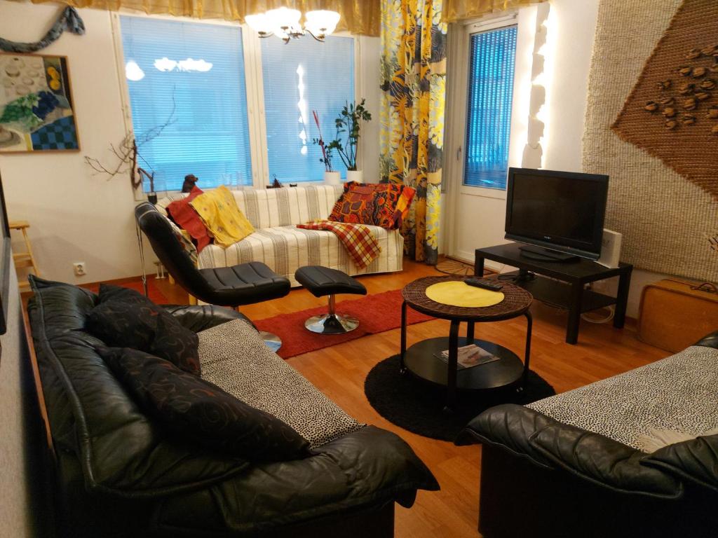 a living room with leather couches and a tv at City Apartment Tulliportti in Kuopio