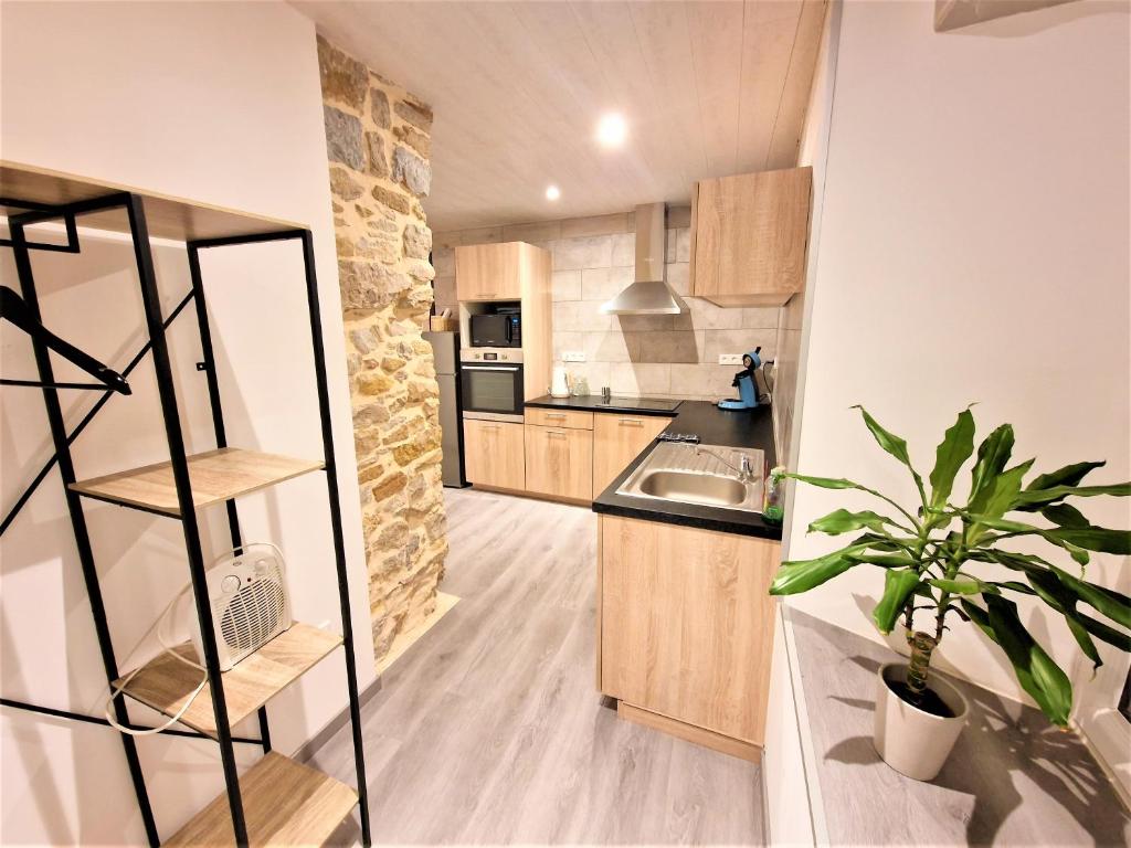 a kitchen with wooden cabinets and a stone wall at L'Atelier 57 - Votre meublé authentique ! in Arbois