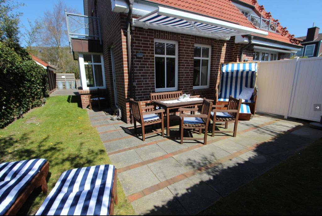 a patio with two benches and a table and chairs at Karkpolder Residenz Haus 3 in Langeoog