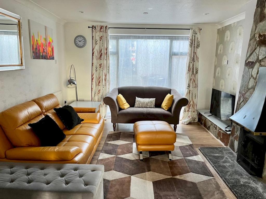 a living room with a leather couch and a chair at Pass the Keys Stylish Family Friendly 3 Bed home with Parking in Bushey